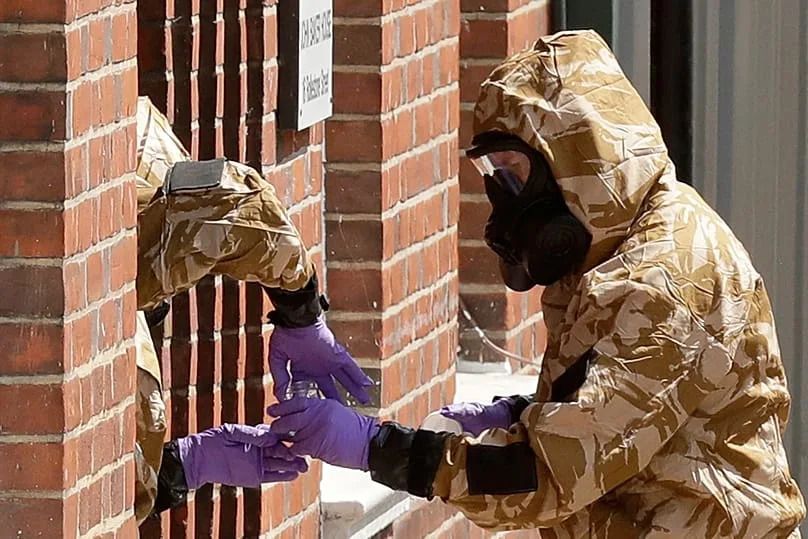 Specialist team members in military protective suits search a fenced off house in Salisbury, 6 July, 2018