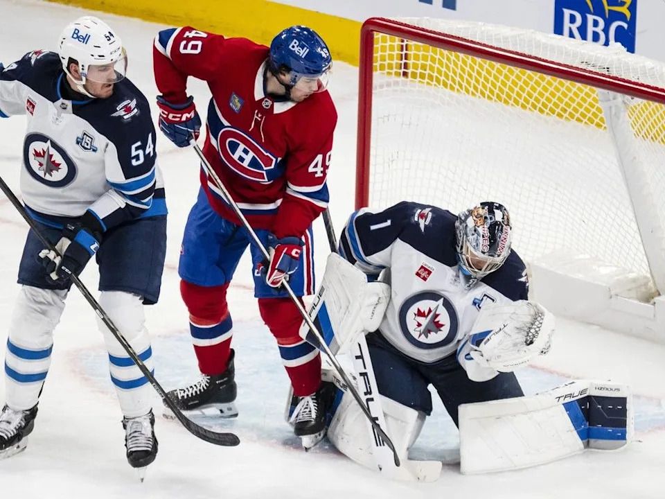 Winnipeg Jets goaltender Eric Comrie (1) makes save on Montreal Canadiens’ Jared Davidson (49) while Jets’ Dylan Samberg (54) defends during second period NHL hockey action, in Montreal on Wednesday, Dec. 3, 2025.