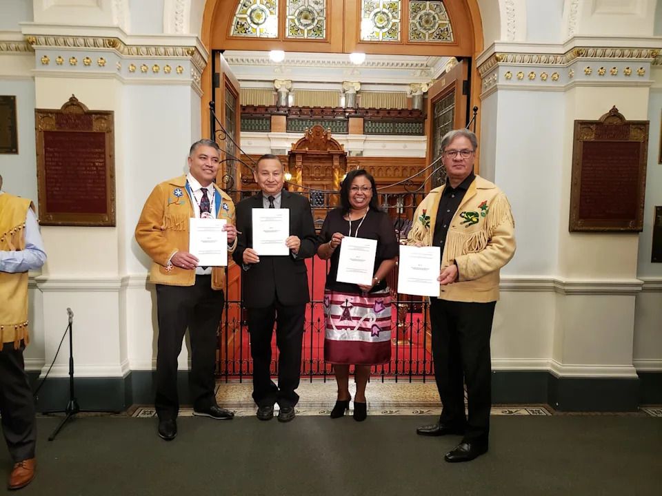 First Nations leadership council representatives hold up printed copies of the UN Declaration bill tabled on Thursday morning in Victoria.
