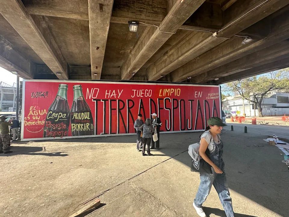 A Christmas-themed Coca-Cola mural was twice painted over with statements saying, “There’s no clean games on stolen lands."
