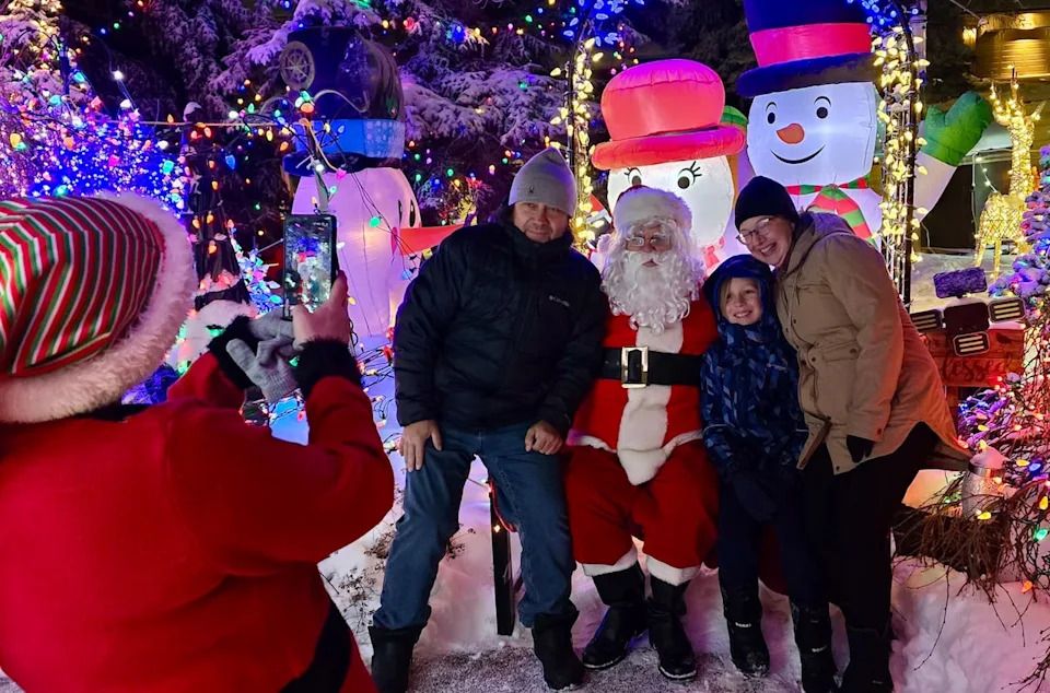 Bev Cuckow (Santa Bevy) poses for a festive photo with the Uttl family at his Scenic Acres home.