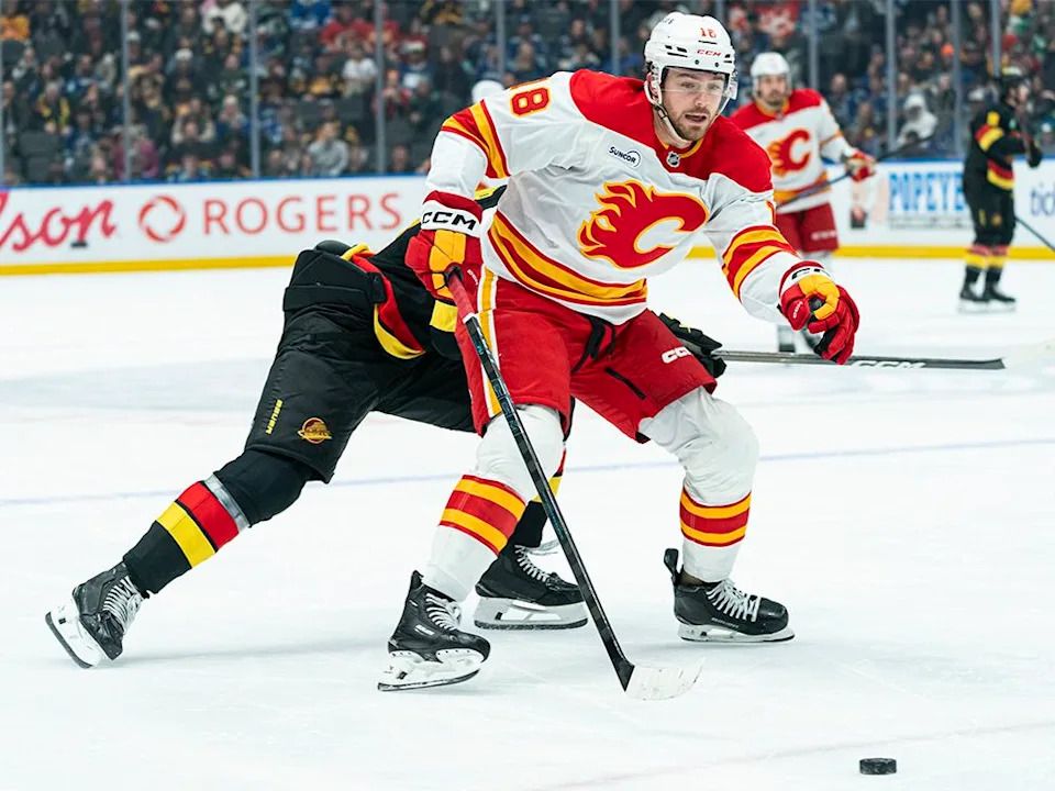John Beecher #18 of the Calgary Flames fights off the check of Elias Pettersson #40 of the Vancouver Canucks while driving to the net during the third period of NHL action at Rogers Arena on Nov. 23, 2025 in Vancouver, Canada.