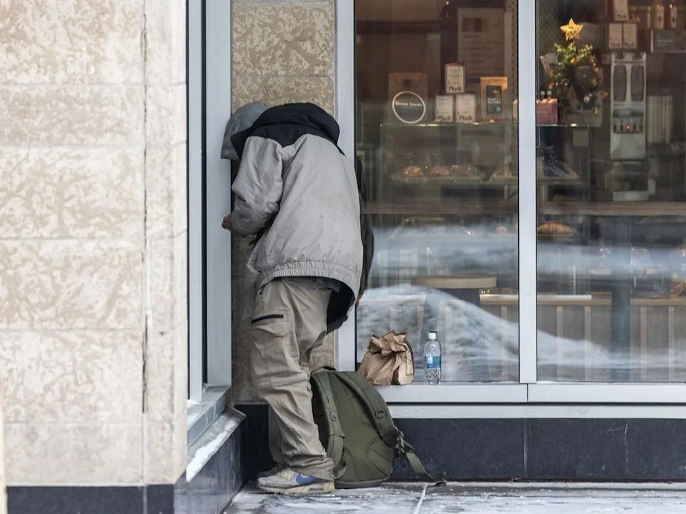 A man huddles in a corner to smoke drugs outside the safe-consumption site at the Sheldon M. Chumir Health Centre in Calgary.