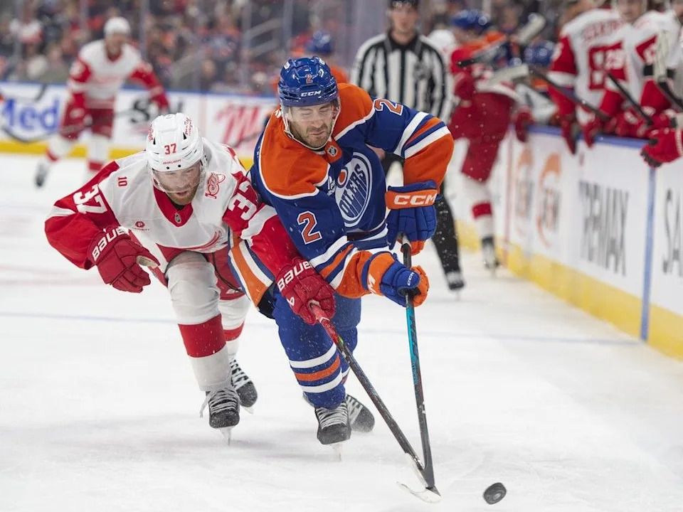 Evan Bouchard (2) of the Edmonton Oilers, keeps the puck from J.T. Compher (37) of the Detroit Red Wings at Rogers Place in Edmonton on Thursday, December 11, 2025.