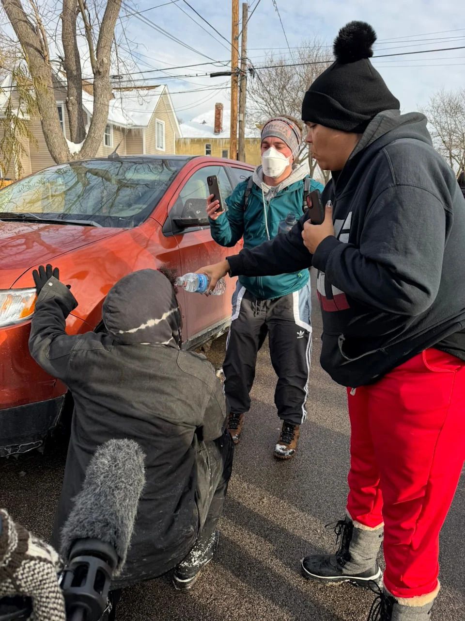 A woman pours water into the eyes of as protestor after ICE fired several pepper pellets into the street during a confrontation at an immigration traffic stop.