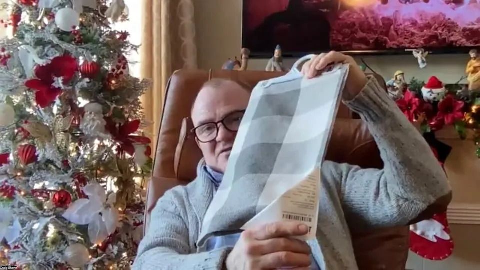 Craig Skene on Zoom holds up an example of one of the thousands of furniture swatches he has brought to Peter Dyck to create shopping bags that are sold to benefit the Steinbach food bank.
