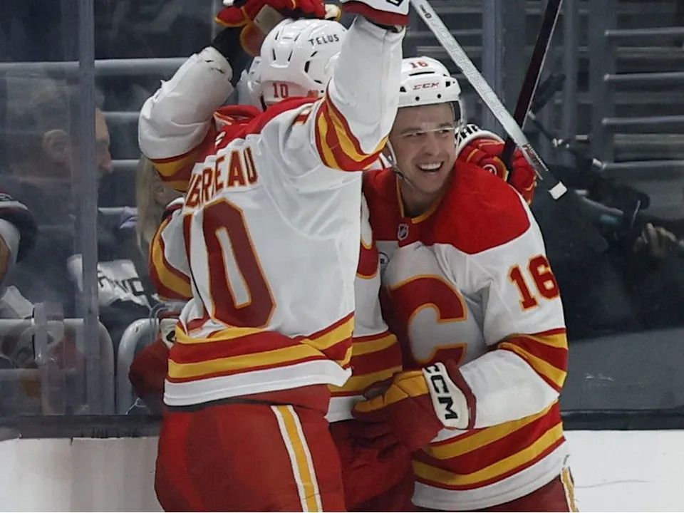 Calgary Flames forward Morgan Frost celebrates his game-wining goal against the Los Angeles Kings with Jonathan Huberdeau and Mackenzie Weegar at Crypto.com Arena in Los Angeles on Saturday, Dec. 13, 2025.