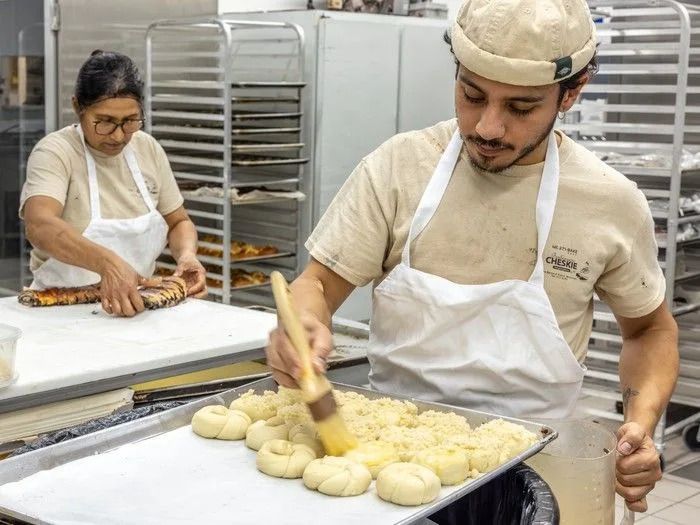 Santy brushes egg on rolls before putting them into the oven while Patmah cuts flat kakosh at Cheskie bakery in Montreal.