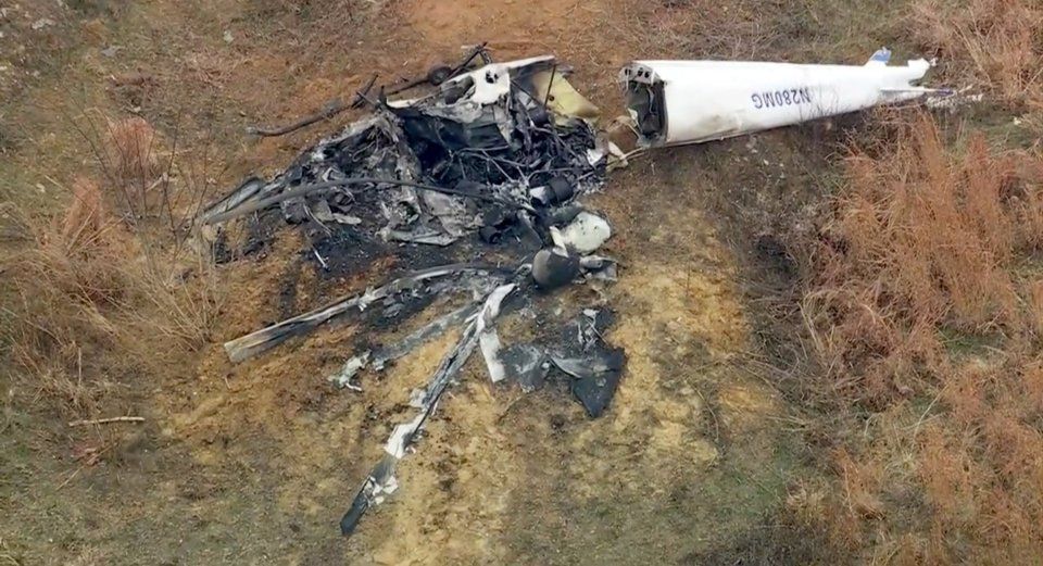 Helicopter crash debris with charred remains and the intact tail section N280MG visible.