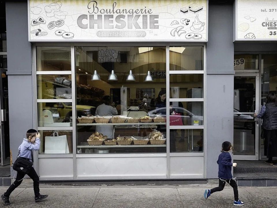 Kids run into Cheskie bakery with their mother in May 2025, shortly before it moved across the street.