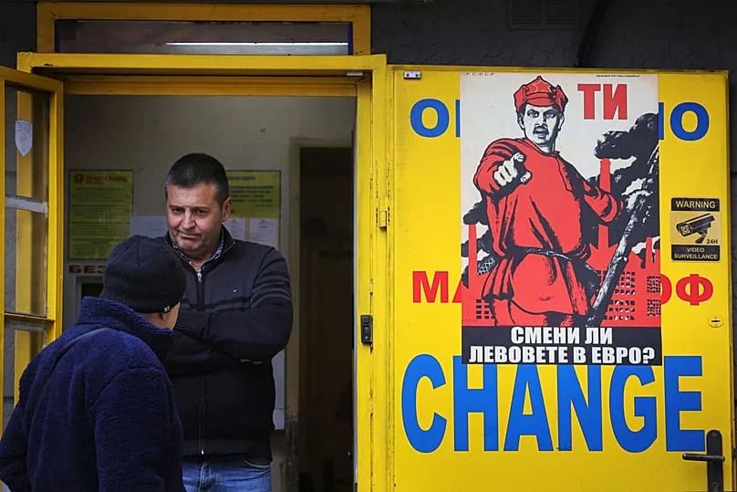 People stand at a currency exchange office with a poster reading "Did you exchange your levs for euros?" in Sofia, 27 December 2025