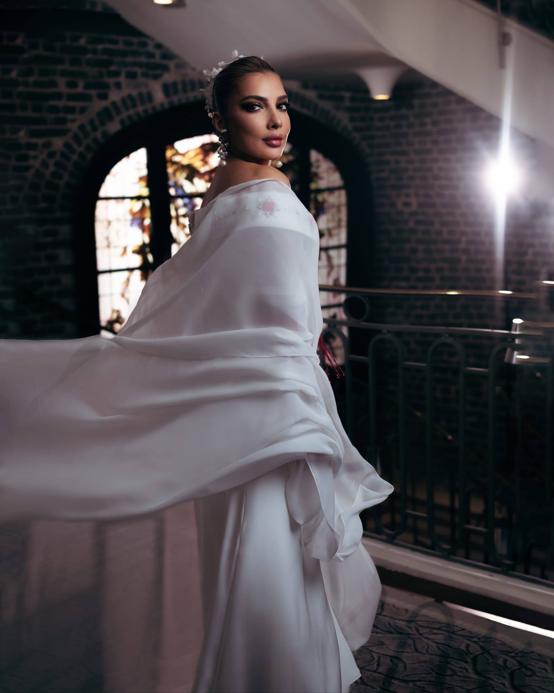 امتدت أكمام الفستان إلى الخلف بأسلوب درابيه، مانحةً الفستان حركة درامية راقية.